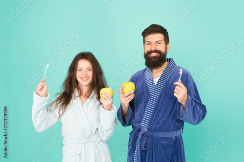 Personal hygiene. Couple in love cleaning teeth. Freshness and cleanliness. Keep teeth healthy. Healthy habits. Brush teeth every morning. Oral hygiene. Couple bathrobes hold toothbrushes and apples © be free