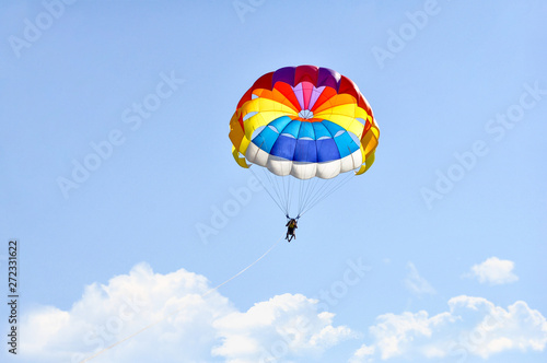 Para sailing using a parachute on background of blue cloudy sky.