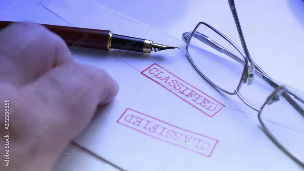 Fingers tapping on classified document Fingers tapping on classified document