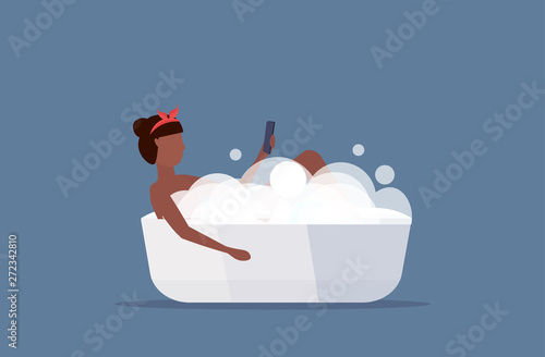 woman lying in bathtub using smartphone social media network communication digital gadget addiction concept african american girl showering flat full length horizontal