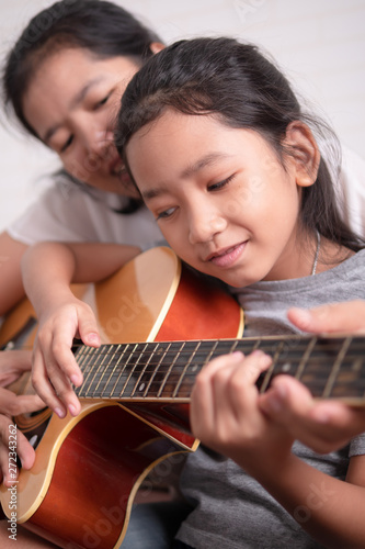 Mom teaching her daughter to play guitar