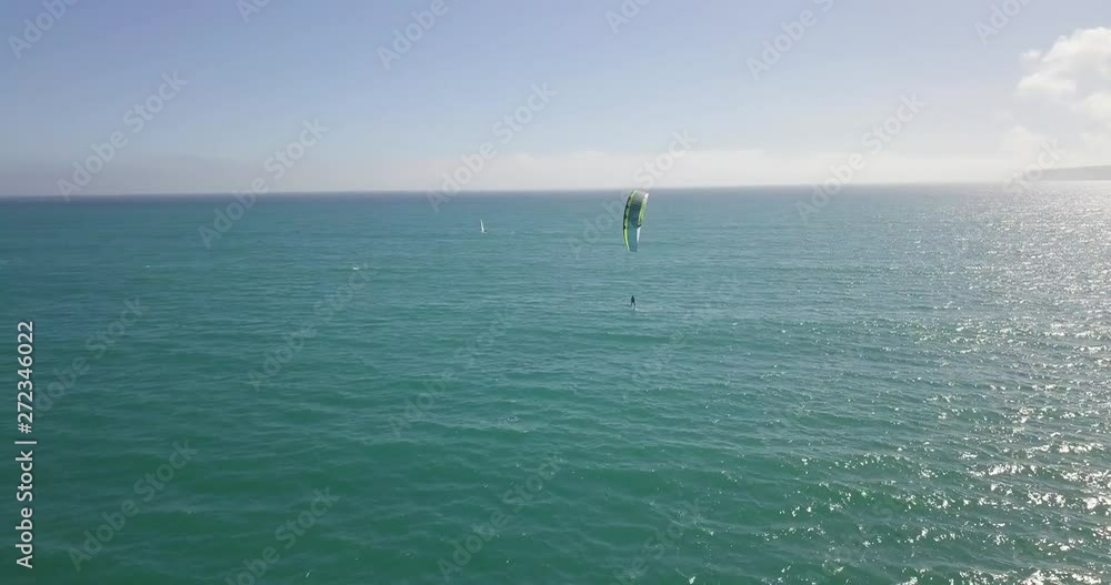 Aerial drone view of a kitesurfer hydrofoiling in mount's bay, Cornwall, UK. Flying alongside him over the blue ocean Aerial drone view of a kitesurfer hydrofoiling in mount's bay, Cornwall, UK. Flying alongside him over the blue ocean