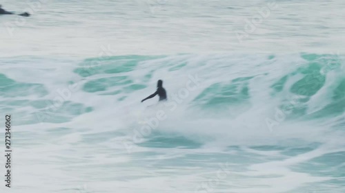 Surfer catches a large wave in Cornwall UK in the cold water on a winters day photo