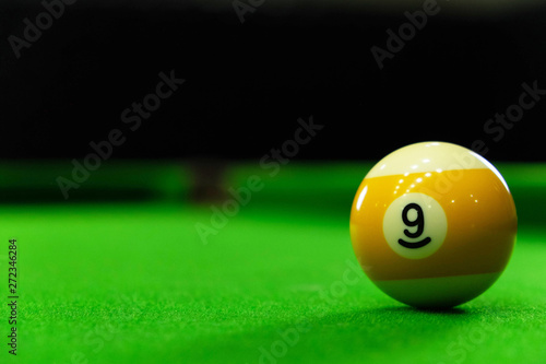 Close-up photos of billiard ball, number 9 and green floor
