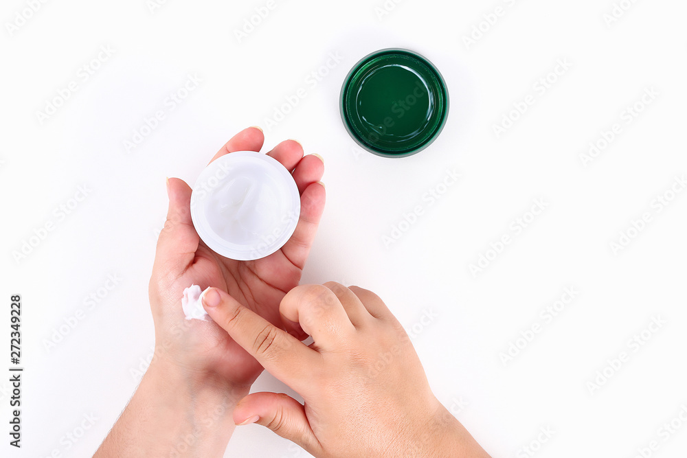 Girl uses hand cream on white background. Top view. Girl uses hand cream on white background. Top view.
