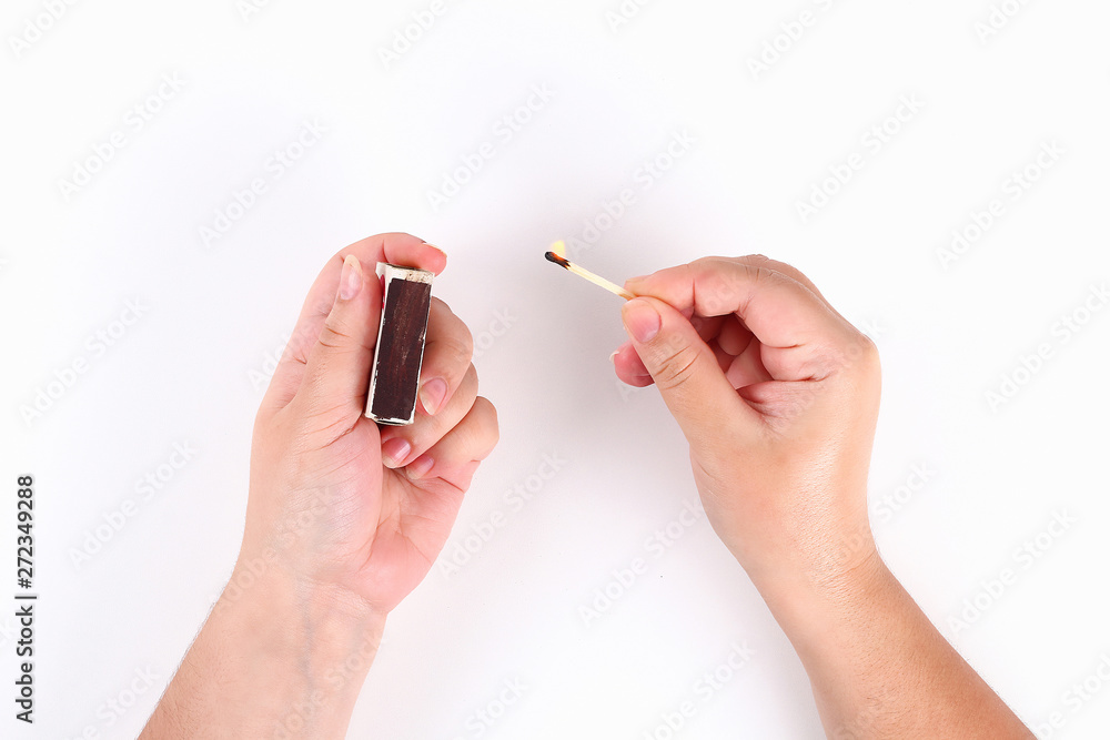 The girl lights a match from a box of matches on white background. Top view. The girl lights a match from a box of matches on white background. Top view.
