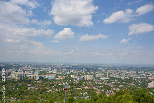 Panoramic view of the city of Almaty, with industrial zone, mountains and sky with clouds. Viewed from Kok tobe, Kazakhstan. © sergfear