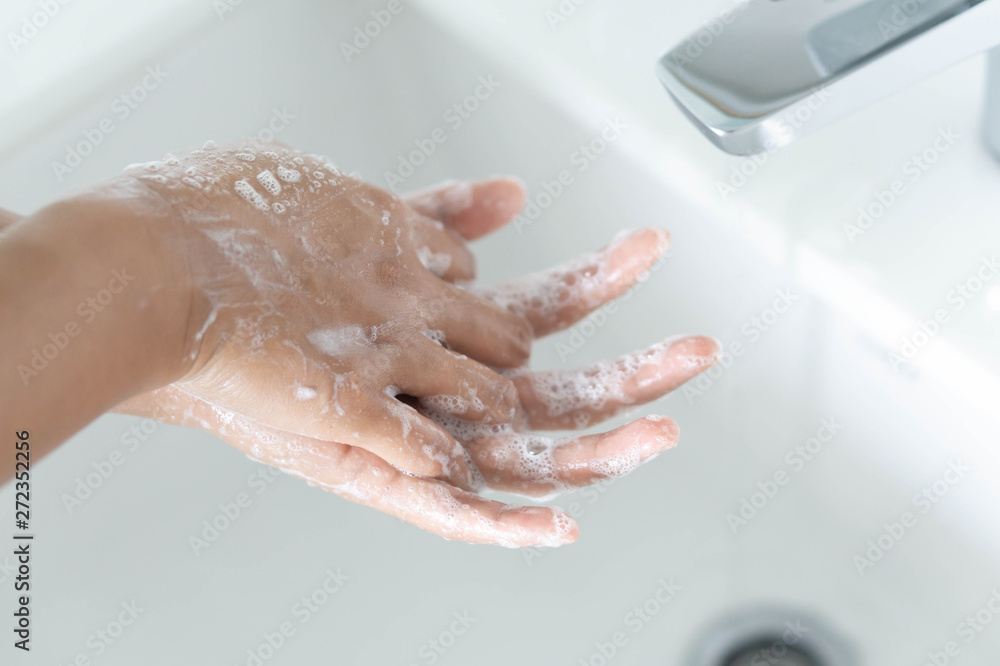 Closeup woman's hand washing with soap in bathroom, selective focus Closeup woman's hand washing with soap in bathroom, selective focus