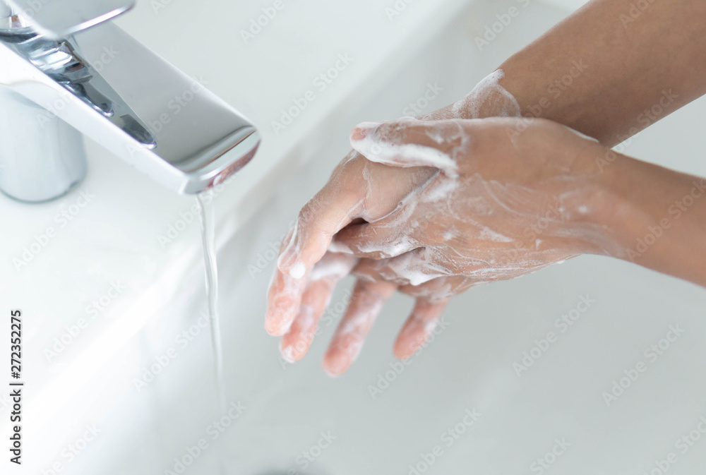 Closeup woman's hand washing with soap in bathroom, selective focus Closeup woman's hand washing with soap in bathroom, selective focus