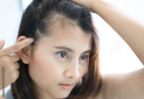 Woman looking reflection in the mirror serious hair loss problem for health care shampoo and beauty product concept