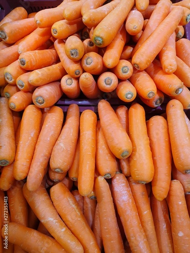 Top view of fresh carrots as a background for sale in the supermarket, for making drinks or salads, healthy food concept