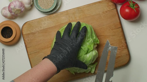 A person with black rubber gloves slicing vegetables 