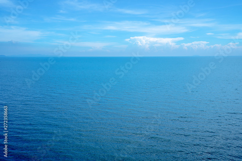 Beautiful white clouds on blue sky over calm sea with sunlight reflection