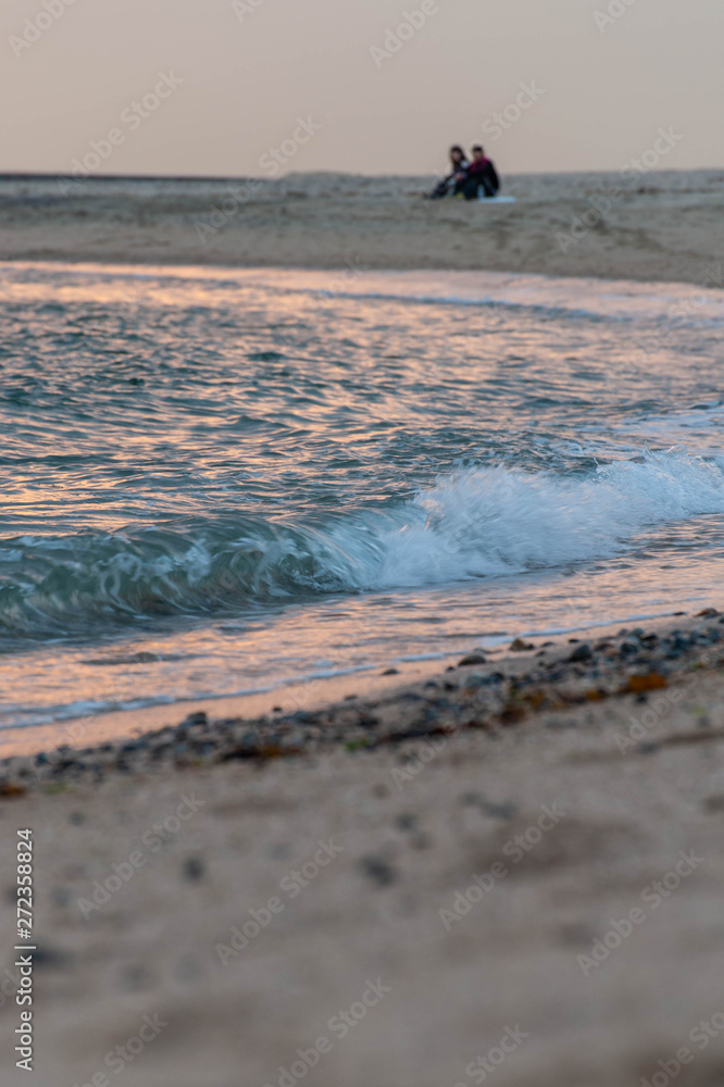 夕日で赤く染まった海と波とカップル