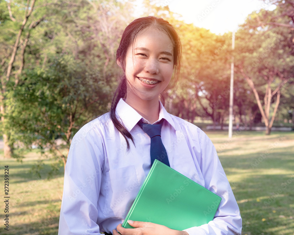 Portrait of thai high school student uniform teen cheerful girl happy and relax holds the books in his hands at the park. Portrait of thai high school student uniform teen cheerful girl happy and relax holds the books in his hands at the park.
