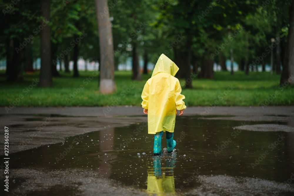 Little boy playing in rainy summer park. Child with umbrella