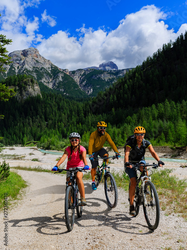Fototapeta Naklejka Na Ścianę i Meble -  Cycling family riding on bikes in Dolomites mountains landscape. Couple cycling MTB enduro trail track. Outdoor sport activity.