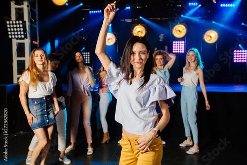 Party, holidays, celebration, nightlife and people concept. Brunette woman clubber dancing surrounded by her friends with smile holidays party relaxing celebrating dancing in night club together.