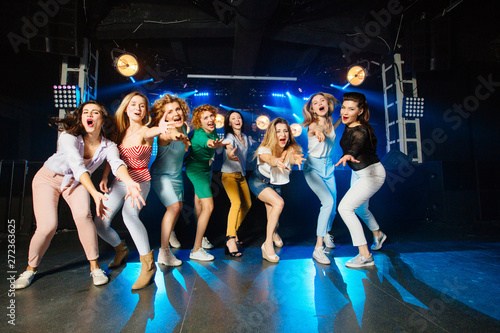 Party, holidays, celebration, nightlife and people concept - group of eight smiling female friends standing in a row shouting waving hands enjoying life at concert in club.