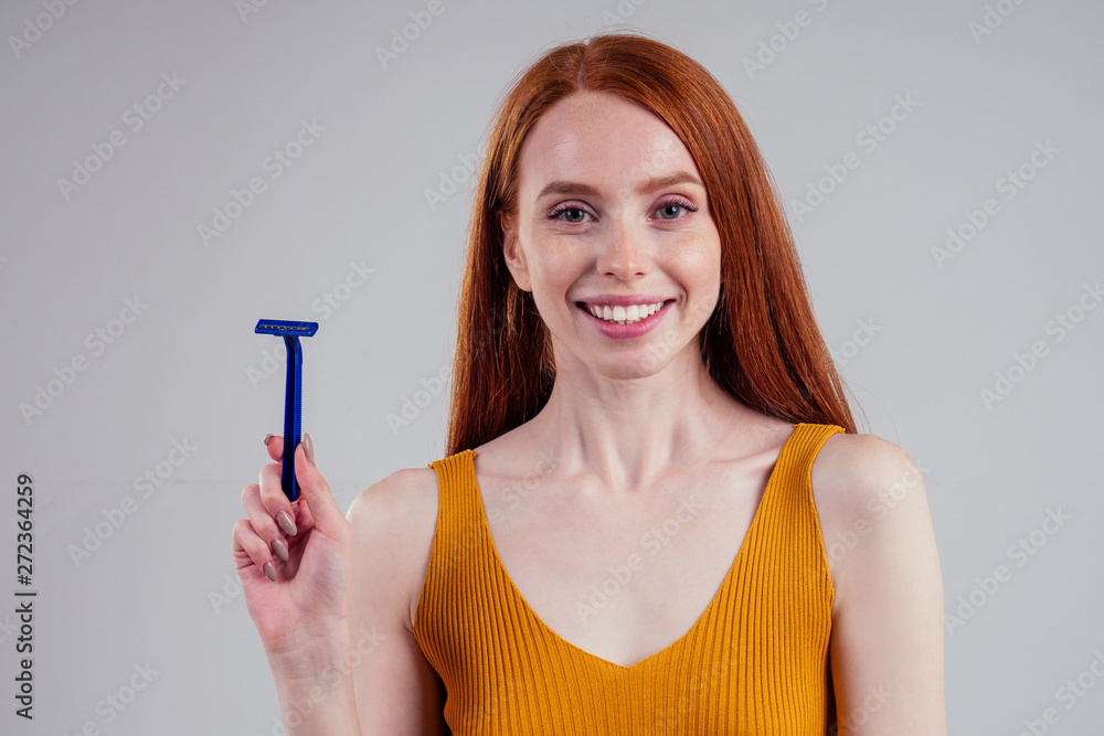 Beautiful young woman with razor and epilator on white studio background Beautiful young woman with razor and epilator on white studio background