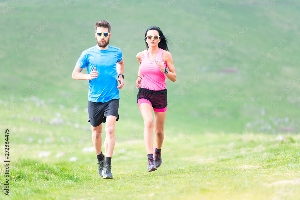 Action of runners in hilly meadows in the summer. Man and woman Action of runners in hilly meadows in the summer. Man and woman