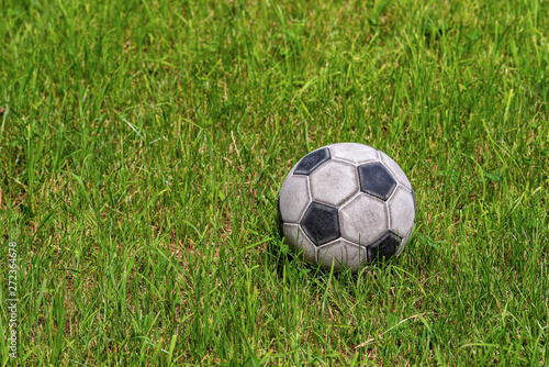 Old leather soccer ball on green grass with copy space, football sport concept