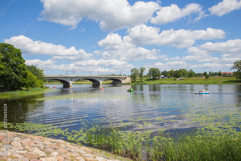 City Jelgava, Latvian Republic. River Lielupe,  people are driving catamaran. Bridge and water. Jun 9. 2019. Travel photo.