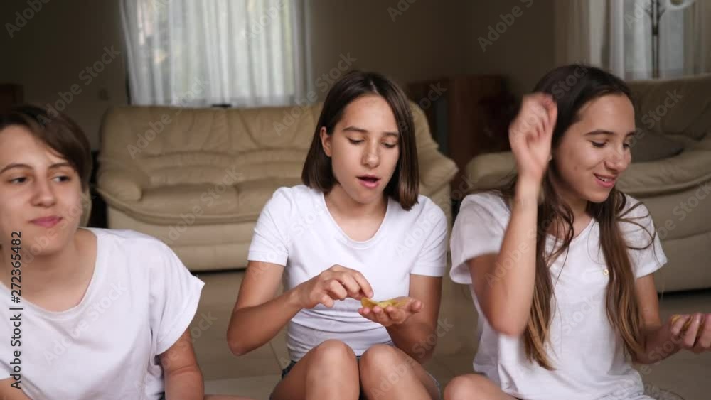 Teenager sisters girls triplet funny sit at home enjoy eat snacks potato chips throwing and catching with a mouth Teenager sisters girls triplet funny sit at home enjoy eat snacks potato chips throwing and catching with a mouth