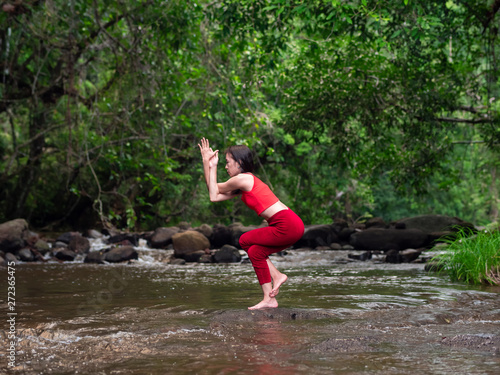 Asian woman practicing or doing yoga at the waterfall. Beautiful Landscape, Natural background, Thailand.