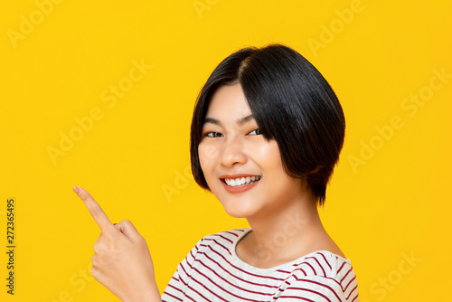 Smiling young Asian woman pointing hand to empty space