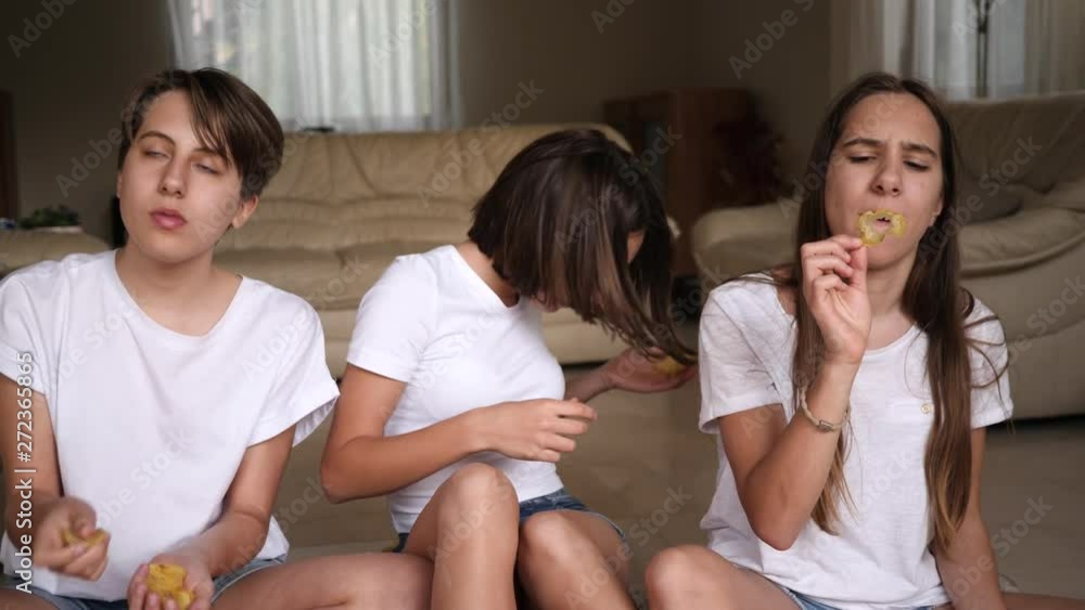 Teenager sisters girls triplet funny sit at home enjoy eat snacks potato chips throwing and catching with a mouth Teenager sisters girls triplet funny sit at home enjoy eat snacks potato chips throwing and catching with a mouth
