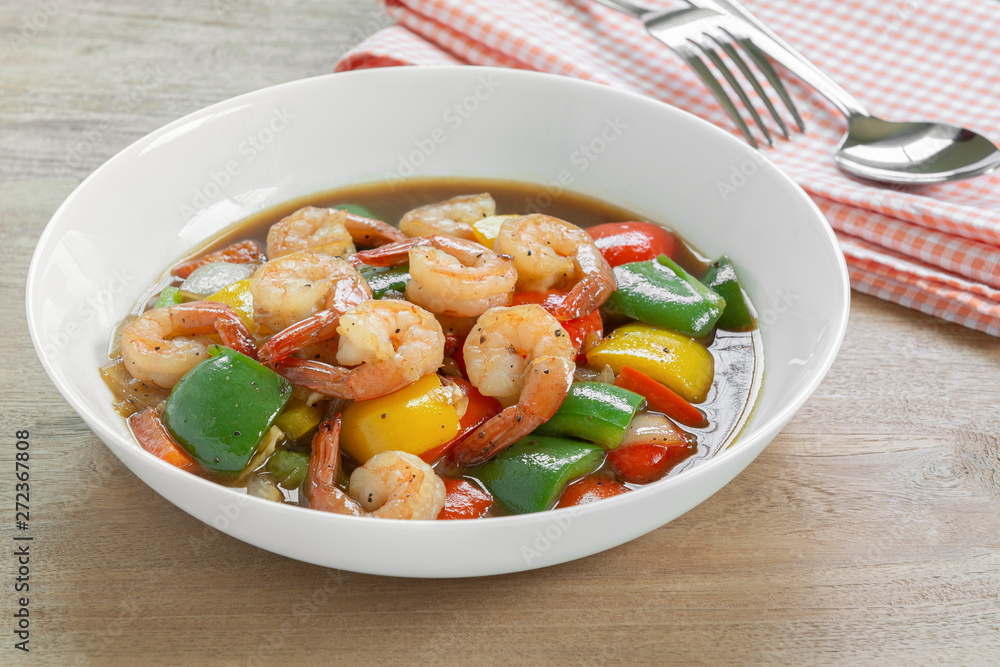 close up of stir fried shrimp with black and sweet pepper in a ceramic plate on wooden table. homemade style food concept. close up of stir fried shrimp with black and sweet pepper in a ceramic plate on wooden table. homemade style food concept.