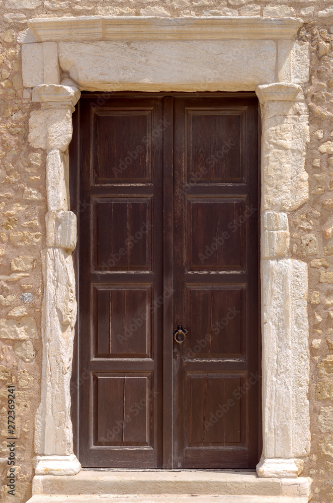 The background old beige stony wall with door The background old beige stony wall with door