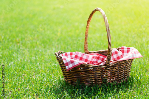 Fototapeta Naklejka Na Ścianę i Meble -  Empty picnic basket with red checkered napkin on the grass.