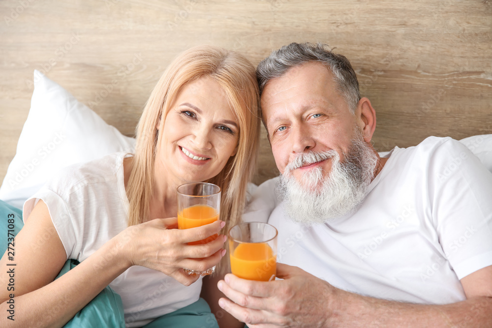 Happy elderly couple drinking juice in bed Happy elderly couple drinking juice in bed