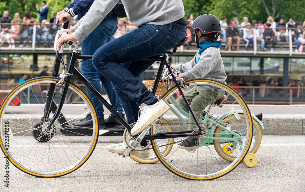 Father and son ride bicycles on walk along the Seine embankment in Paris