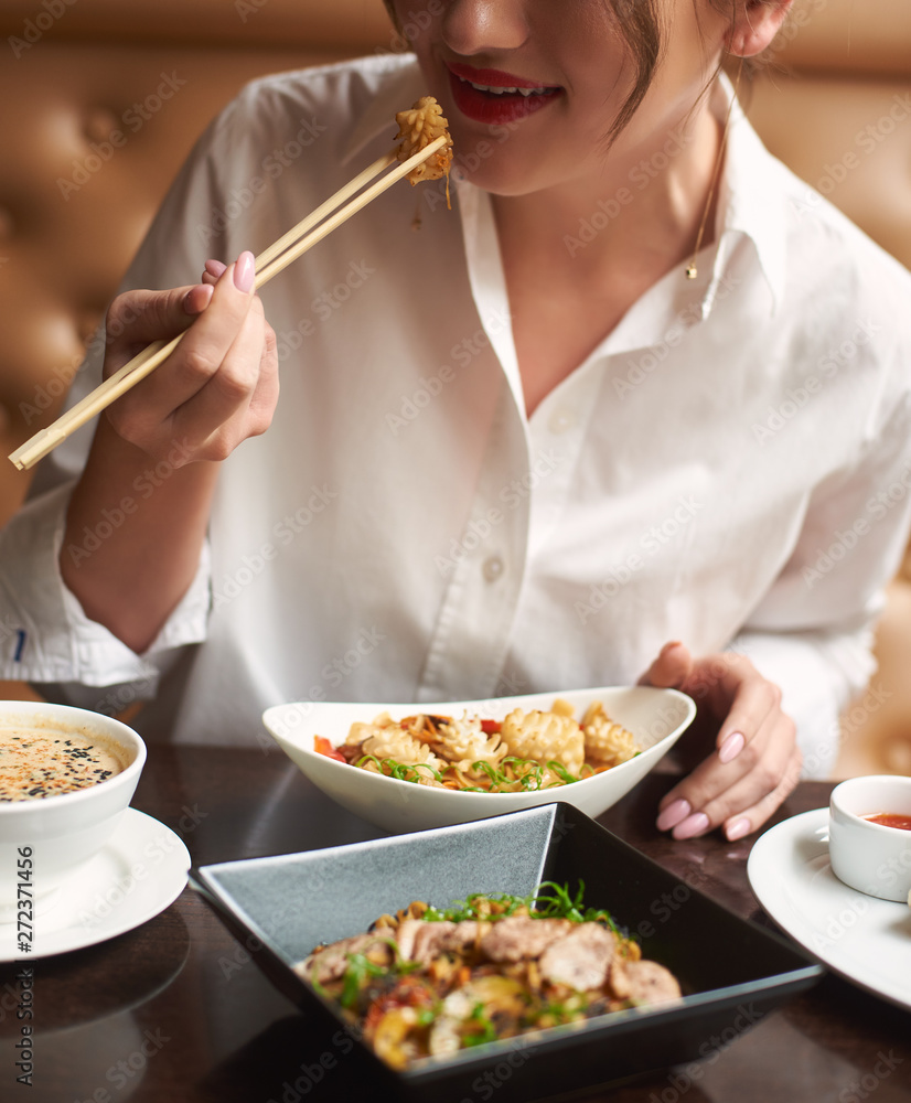Crop of pretty woman in white blouse with red lips ordering meal in luxury Japanese restaurant. Lady eating four course lunch including soup, tempura shrimps, noodles and warm salad. Crop of pretty woman in white blouse with red lips ordering meal in luxury Japanese restaurant. Lady eating four course lunch including soup, tempura shrimps, noodles and warm salad.