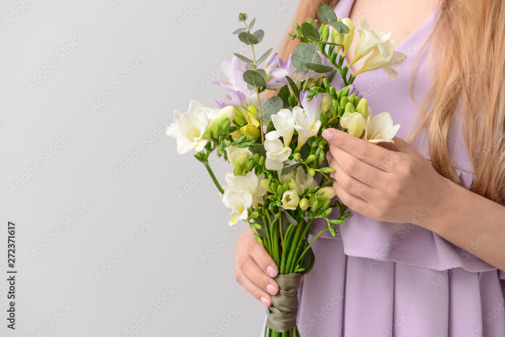 Woman with beautiful freesia flowers on light background Woman with beautiful freesia flowers on light background
