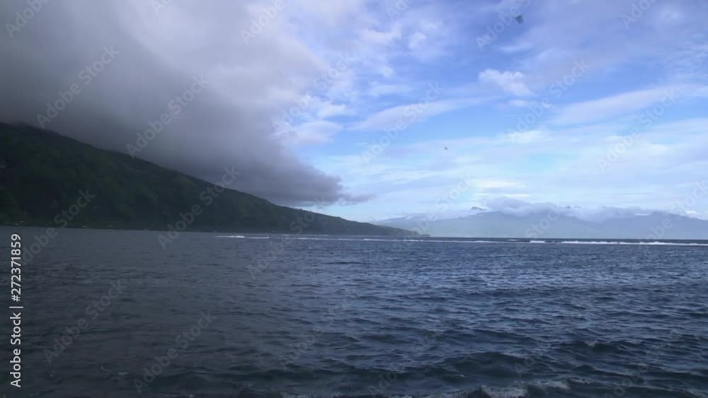 Dark Rain Clouds on Island View from Ocean While Two Birds Fly By. Dark Rain Clouds on Island View from Ocean While Two Birds Fly By.