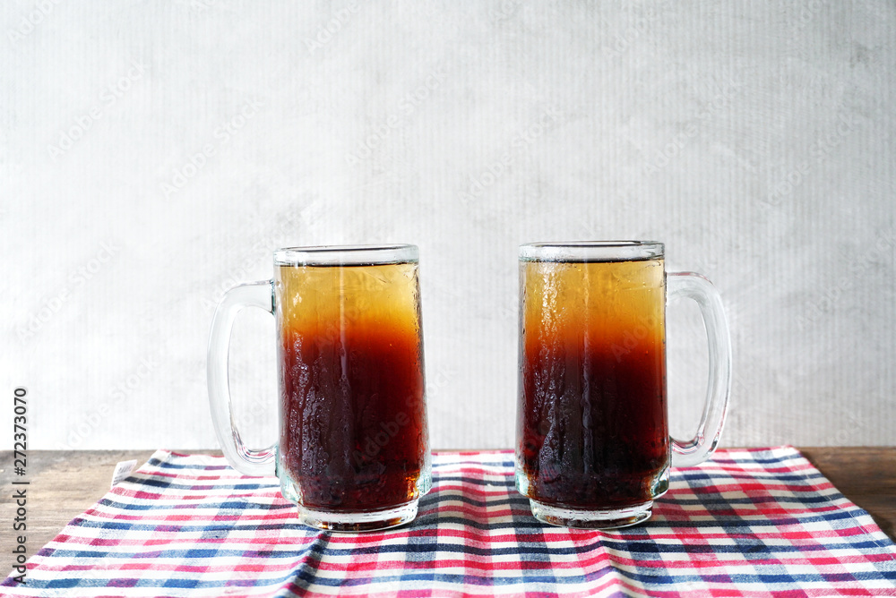 Two glasses of cool soft drink lay on cloth on the table with gray background. Two glasses of cool soft drink lay on cloth on the table with gray background.