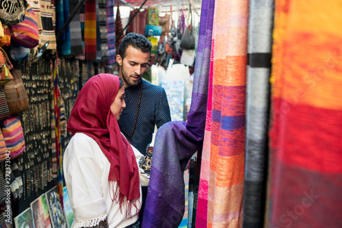 Smiling young muslim couple shopping carpets in a textile store