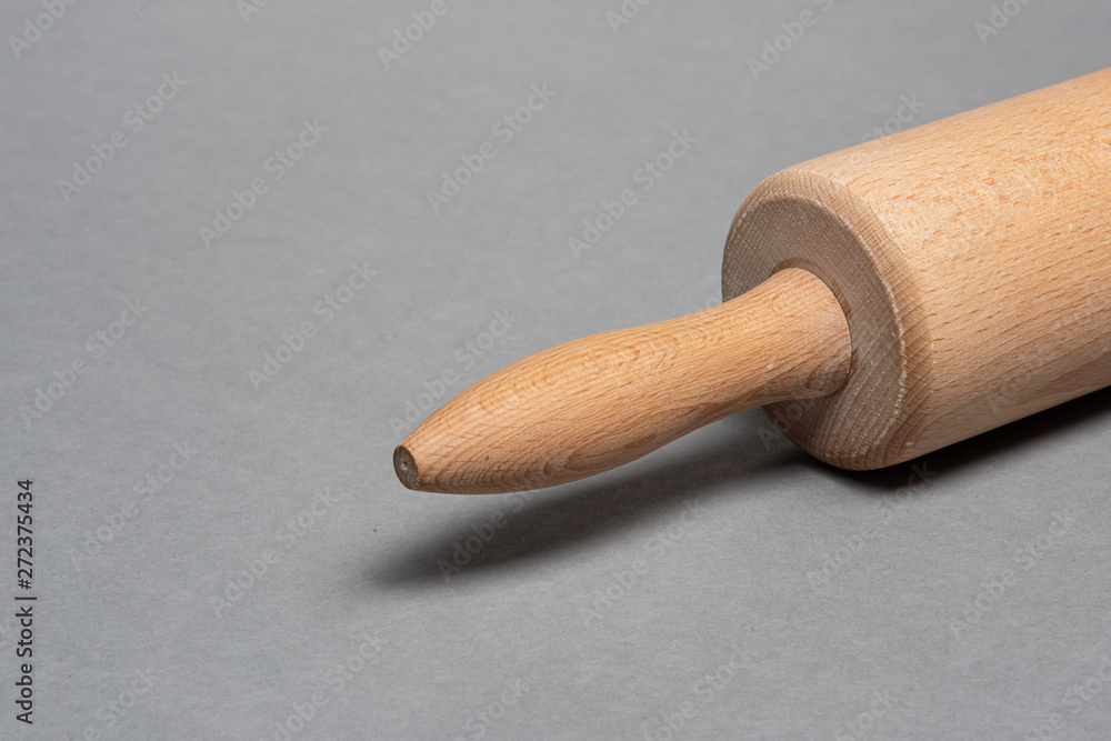 Woden rolling pin on grey background.