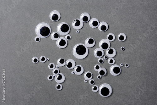 Many different sizes of googly eyes on grey background. photo