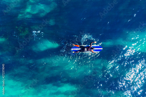 Surfer rows up to catch crest of wave in blue ocean. Concept surfing. Top view
