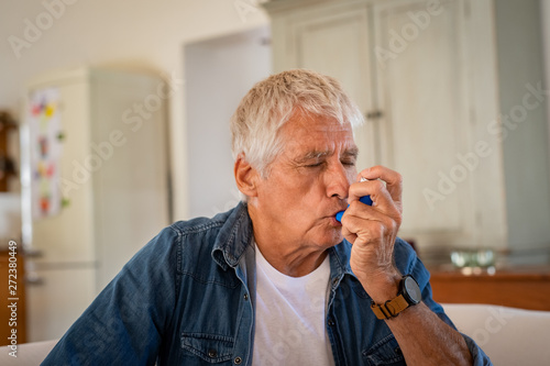 Senior man using asthma pump photo
