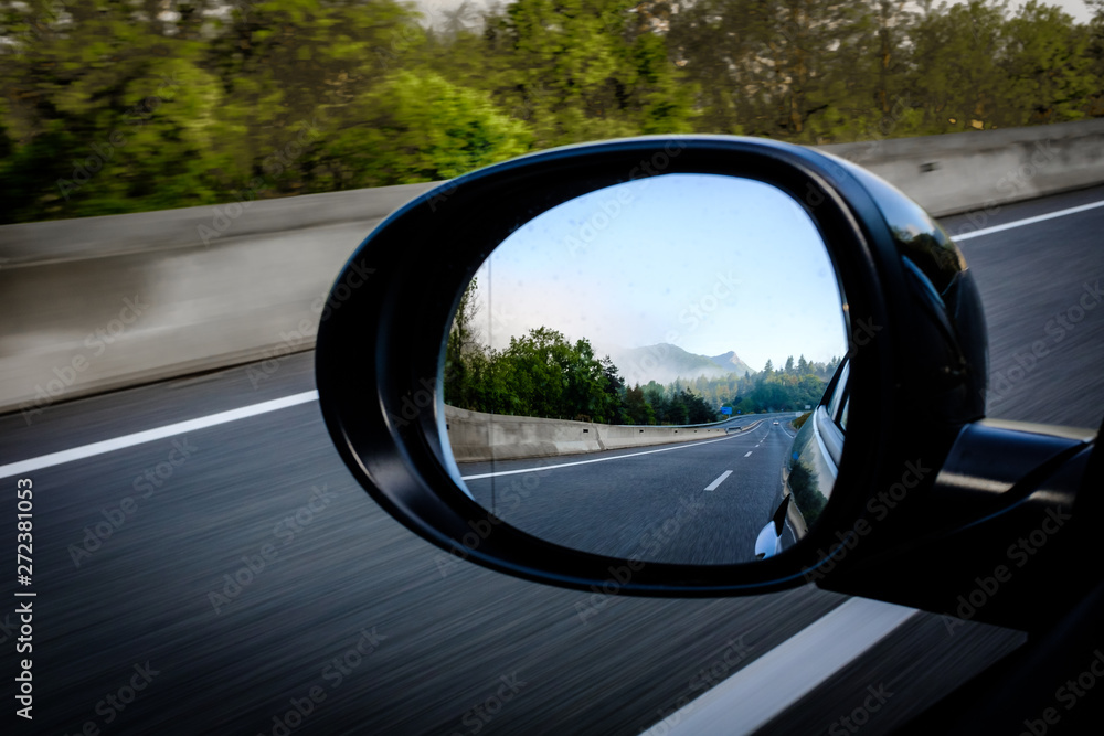 Left oval mirror car highway reflection on a blue sunny sky
