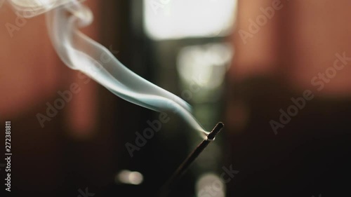 Smoke from incense stick on glass table in the morning with strong light photo