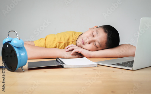 Sleeping Asian preteen boy whild doing homework at home, lifestyle concept. photo