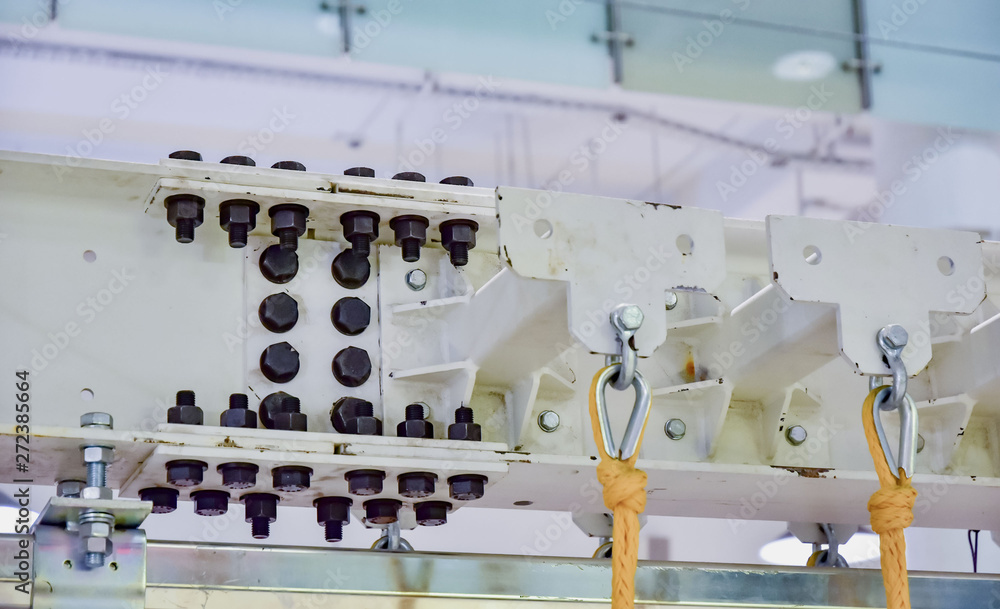 bolted steel I-beam connection. the beam is painted white. black bolts