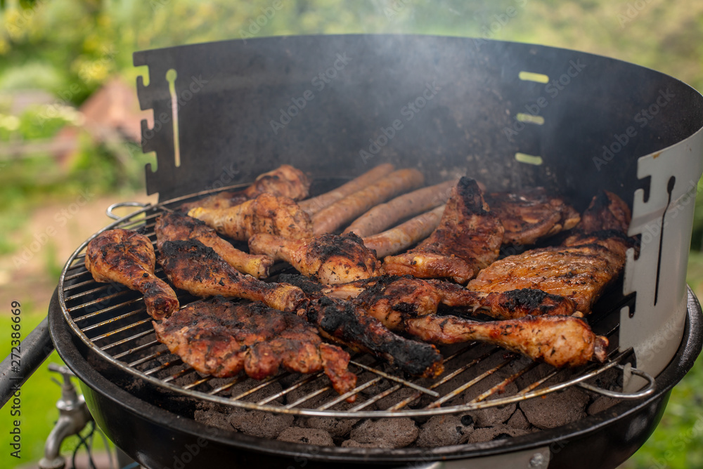 a small grill full of roasted meat on the background of nature, in the summer, warm evening